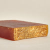 A cross-section of an organic turmeric soap bar showing the solidifying texture and color gradient from orange to yellow.