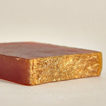 A cross-section of an organic turmeric soap bar showing the solidifying texture and color gradient from orange to yellow.
