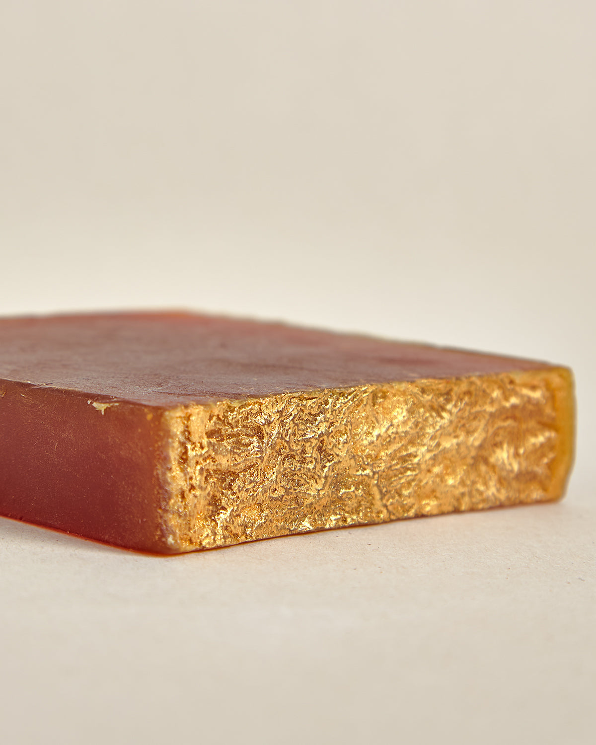 A cross-section of an organic turmeric soap bar showing the solidifying texture and color gradient from orange to yellow.